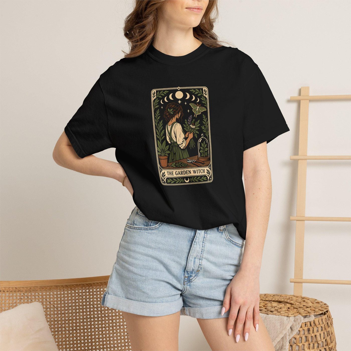 Person wearing a black garment-dyed t-shirt with a garden witch tarot card print