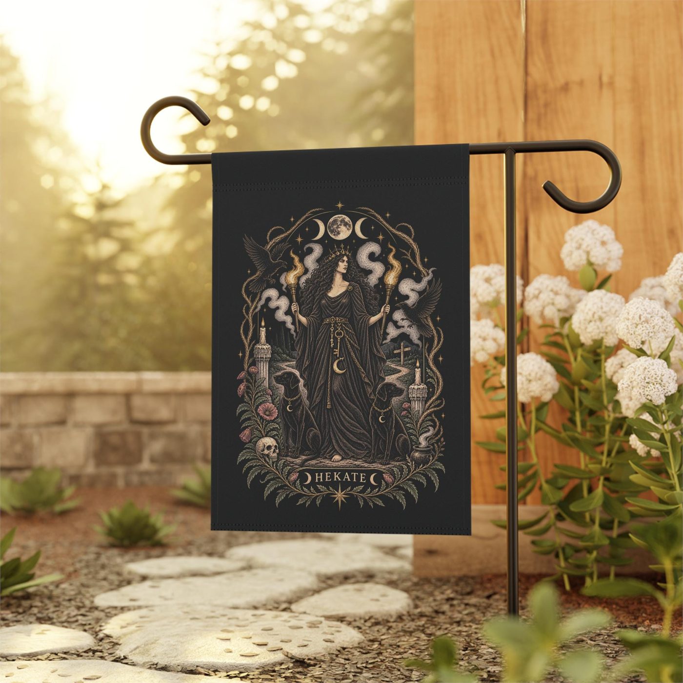 Charcoal garden flag printed with Hekate, hanging from a black iron stand in a garden